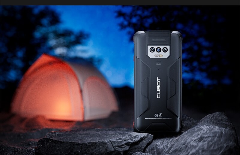 Telefono CUBOT su roccia, tenda illuminata sullo sfondo notturno.